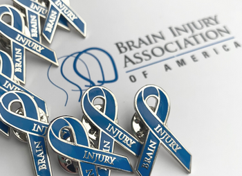 Brain injury awareness pins in the palm of a woman's hand