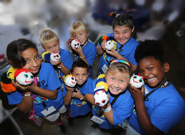 A group of smiling children with caterpillar plush toys.