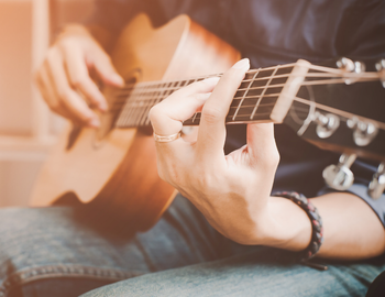 A young woman in bright green shirt plays guitar