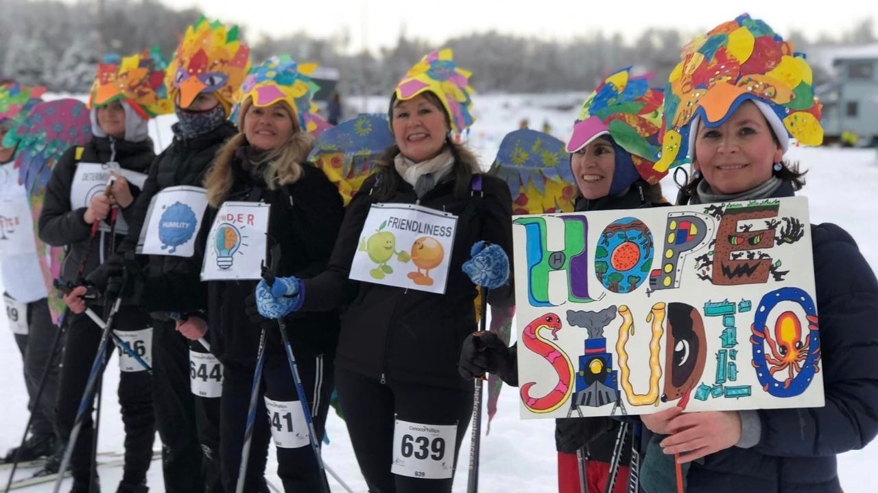 Members of Hope stand in a row wearing costumes and holding signs for 'Hope Studios.'