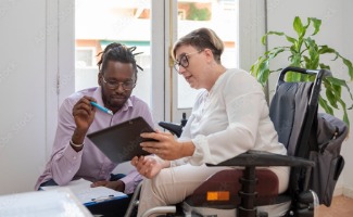 A man helps a woman who experiences a disability with her finances.