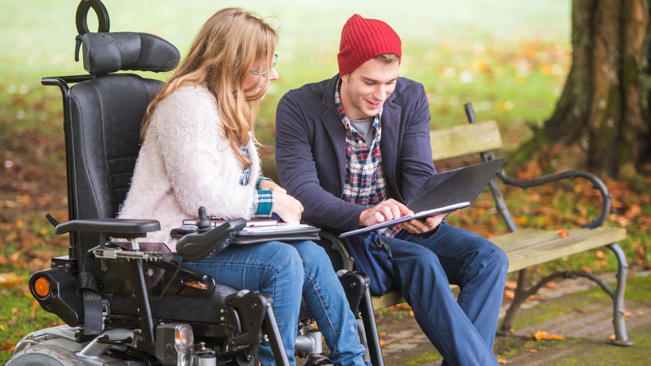 A man helps a woman who experiences a disability with her finances.