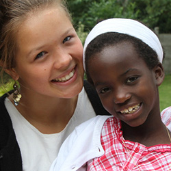 Two young girls stand side-by-side and smile at the camera