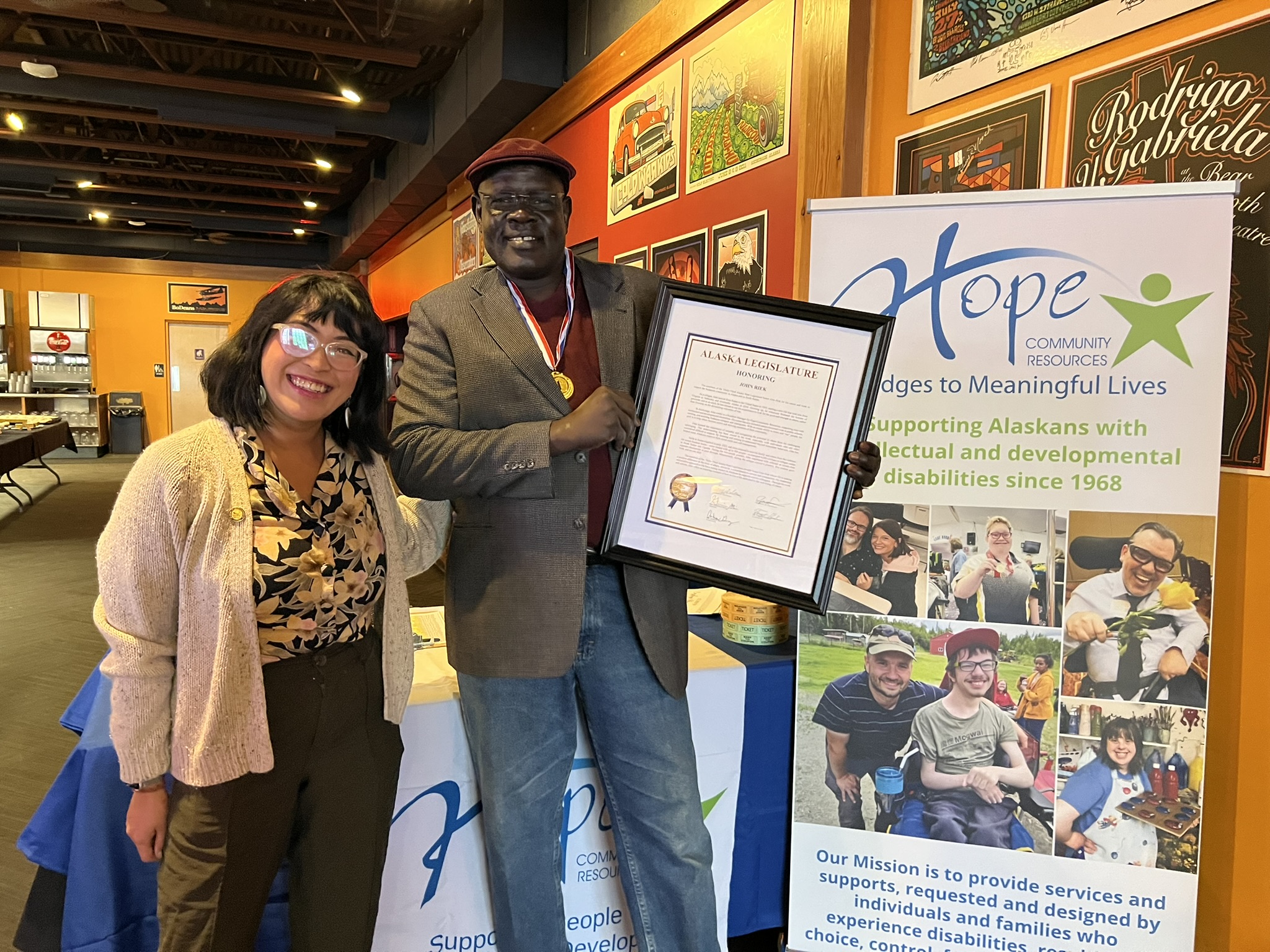 John Riek holds his Legislative Citation certificate and stands next to Representative Genevieve Mina