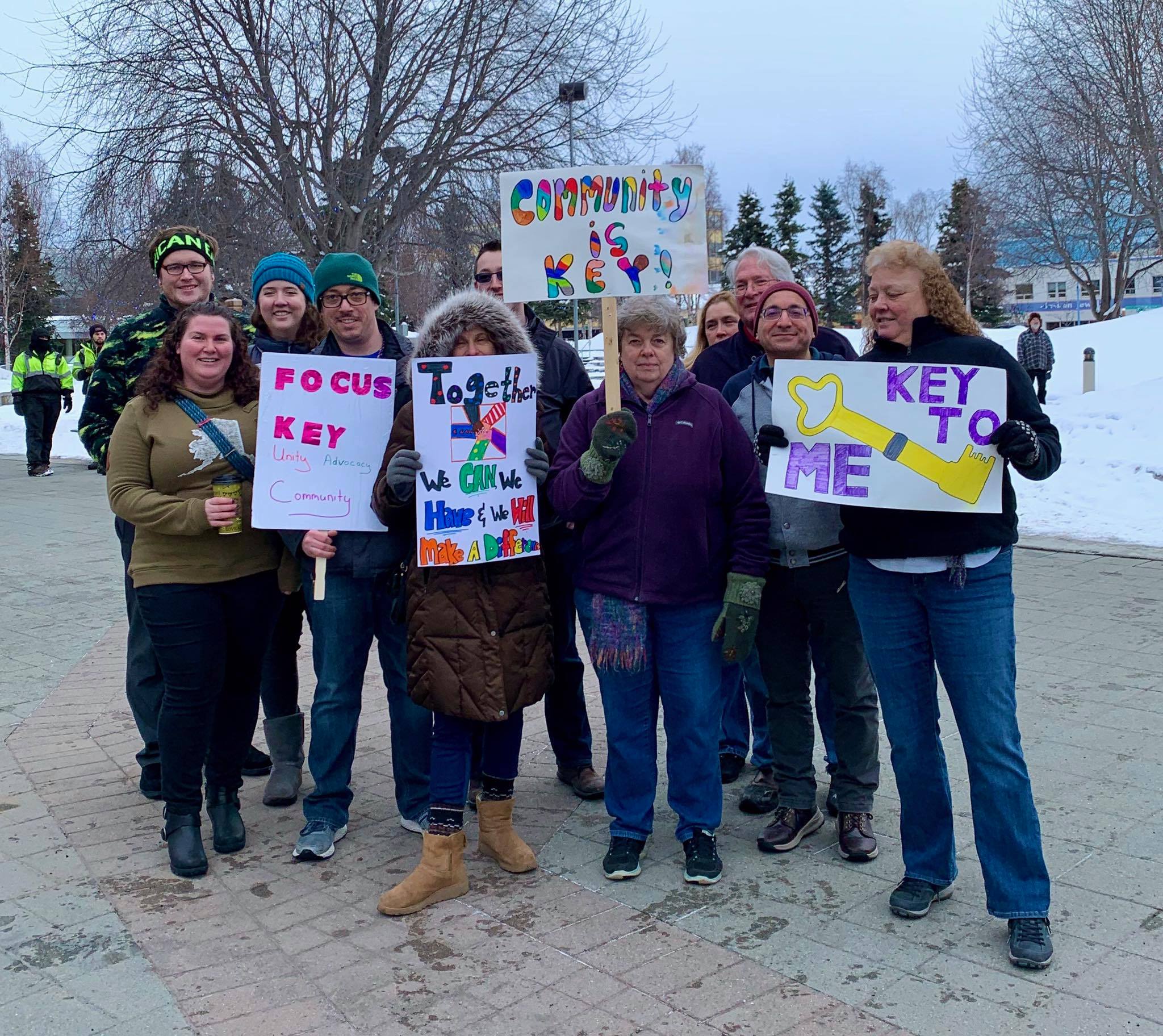 A large group of community members march through downtown Anchorage during winter with advocacy signs
