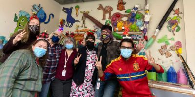 A group of seven staff members from Hope's Discovery Center stand together. Several of them hold up peace signs and are wearing face masks.