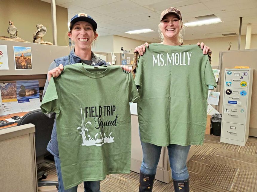 CWA Environmental Educator Arianna Oneto, left, and CWA Education Coordinator Molly Maupin, right, hold up their "Field Trip Squad" T-shirts made by a coworker.