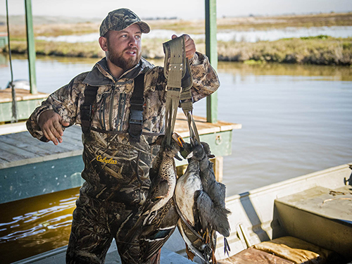 A guide unloads a strap of ducks at California Waterfowl's Duck Camp.
