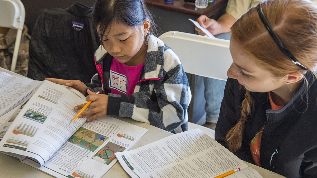 Aspiring hunters look through hunter education book