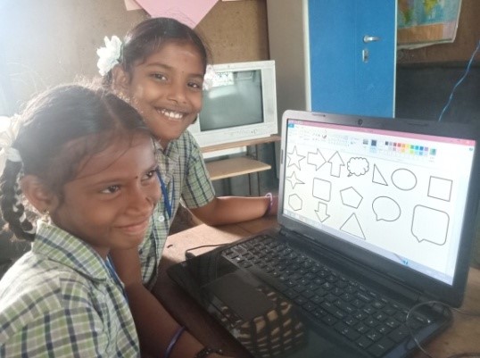 Two girls in India sit in front of a laptop provided by the Mobile Computer Lab, part of the larger English+ program