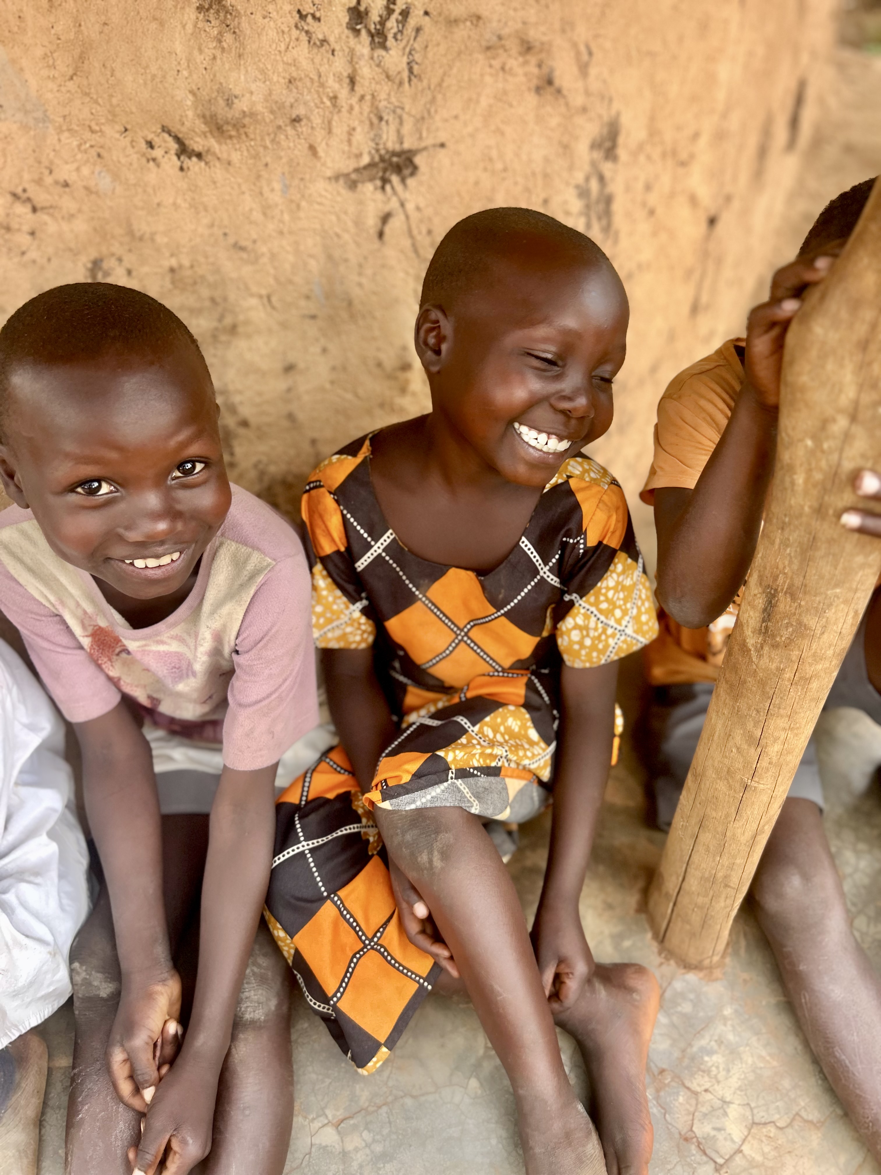 group of kids huddled under hut smiling